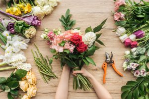 cropped-view-of-florist-holding-flower-bouquet-on-wooden-table